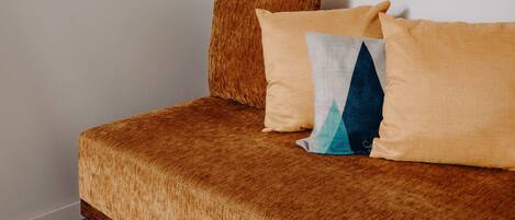 A bed with a textured brown cover and two pillows, one with a geometric pattern.