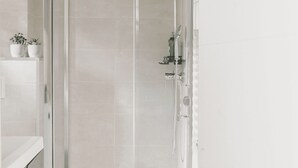 A modern bathroom with a glass shower enclosure, white tiles, and a small potted plant on the countertop. - Vacation Apartment Rental - La Suite D'Hélène in Scionzier (SCIONZIER)