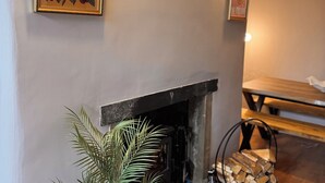 Ein gemütliches Wohnzimmer mit Kamin, einem gerahmten Bild mit dem Schriftzug "EY UP" und einer Decke aus Holzbalken.
