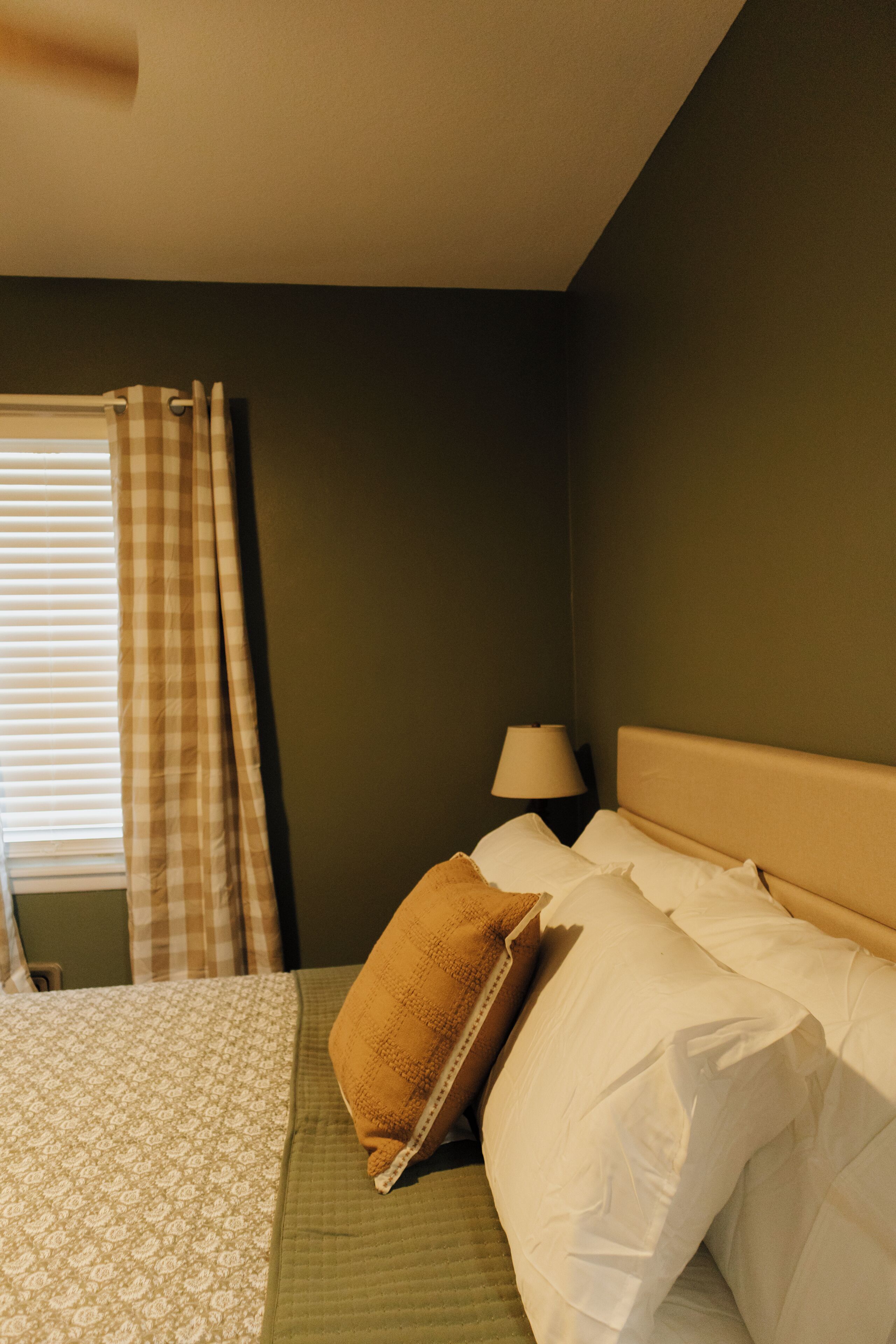 Een hotelkamer met een bed, een lamp en een raam met gordijnen.