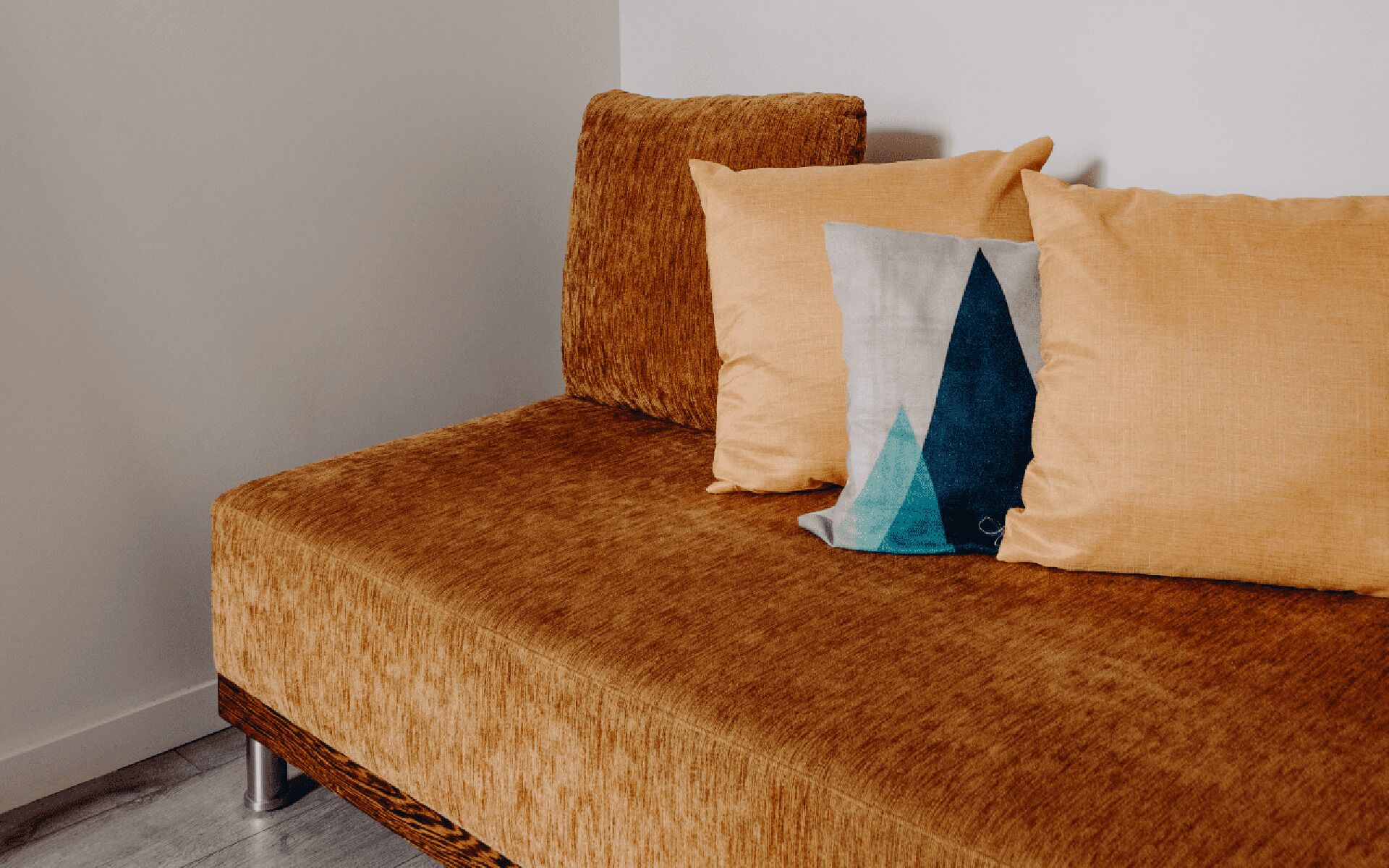 Un letto con copriletto marrone e trama decorativa e due cuscini, uno con motivo geometrico.