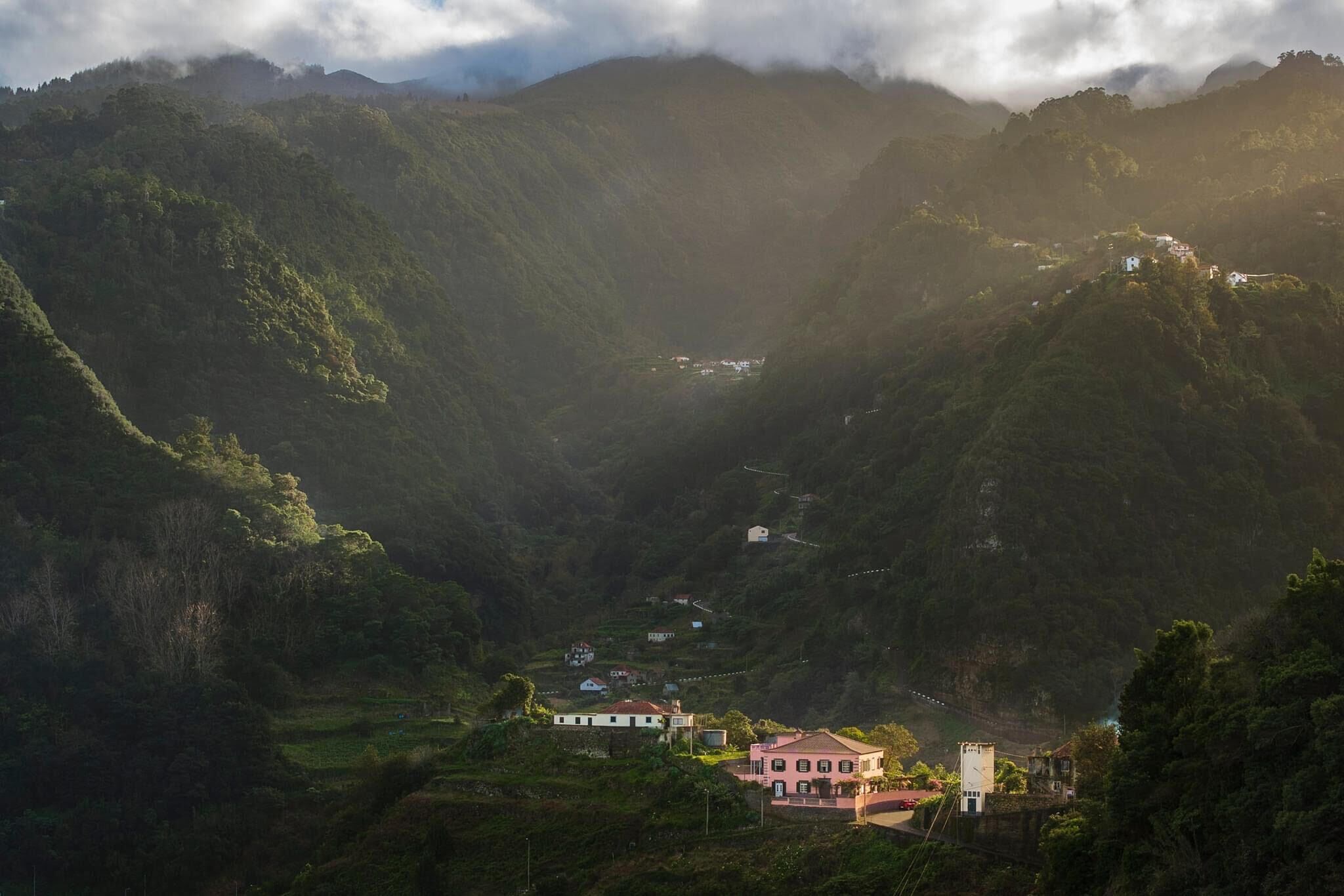 Una valle con una casa immersa nel verde e circondata da colline.
