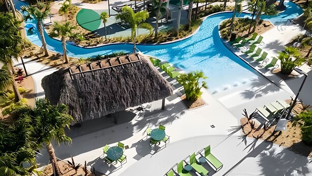 A resort pool area with multiple swimming pools, lounge chairs, and a waterfall feature.