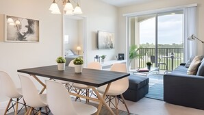 Een moderne woonkamer met een eethoek, grote ramen en een balkon.