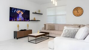 Un salon moderne avec un téléviseur à écran plat, une table basse, un canapé et une horloge au mur.