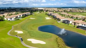 Un parcours de golf avec des bunkers, un étang agrémenté d’une fontaine et, au loin, des immeubles résidentiels.