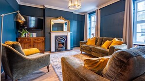 A living room with two sofas, a fireplace, a mirror, and a bookshelf. - Church House - sleeps 6 guests  in 3 bedrooms (Beaumaris)