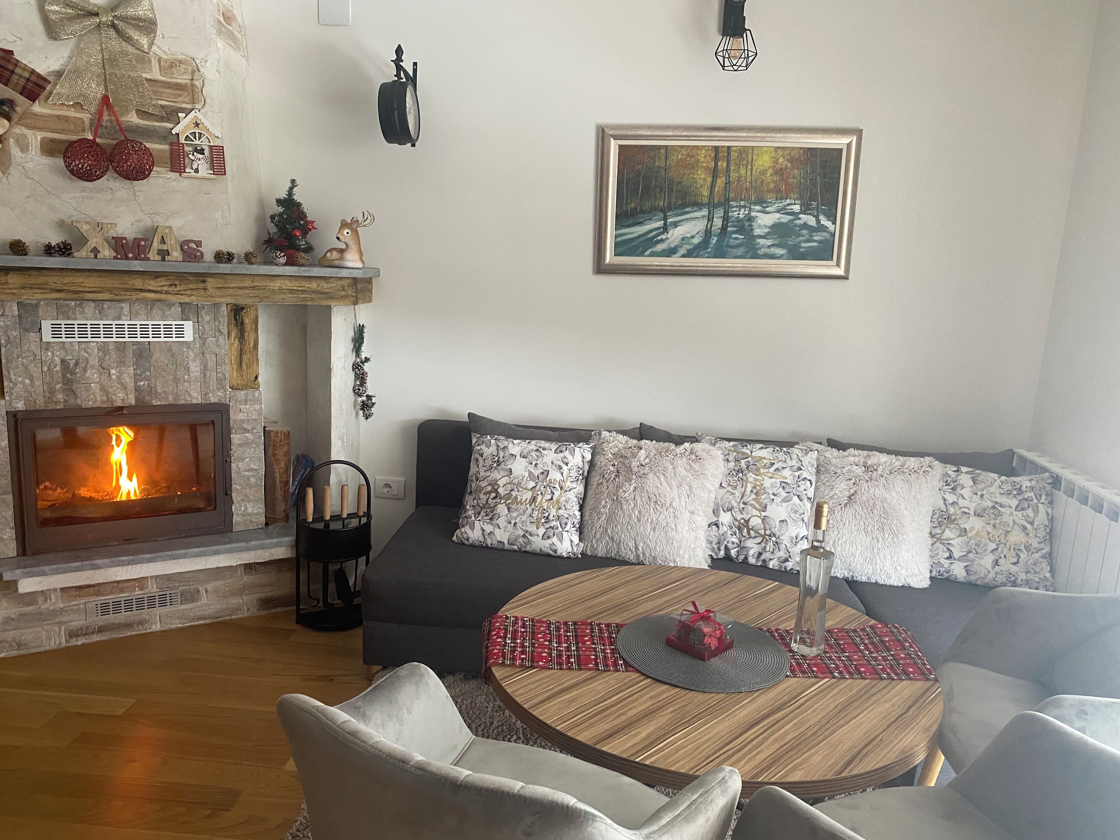 A cozy living room with a fireplace, a sofa set, a round coffee table, and a painting on the wall.