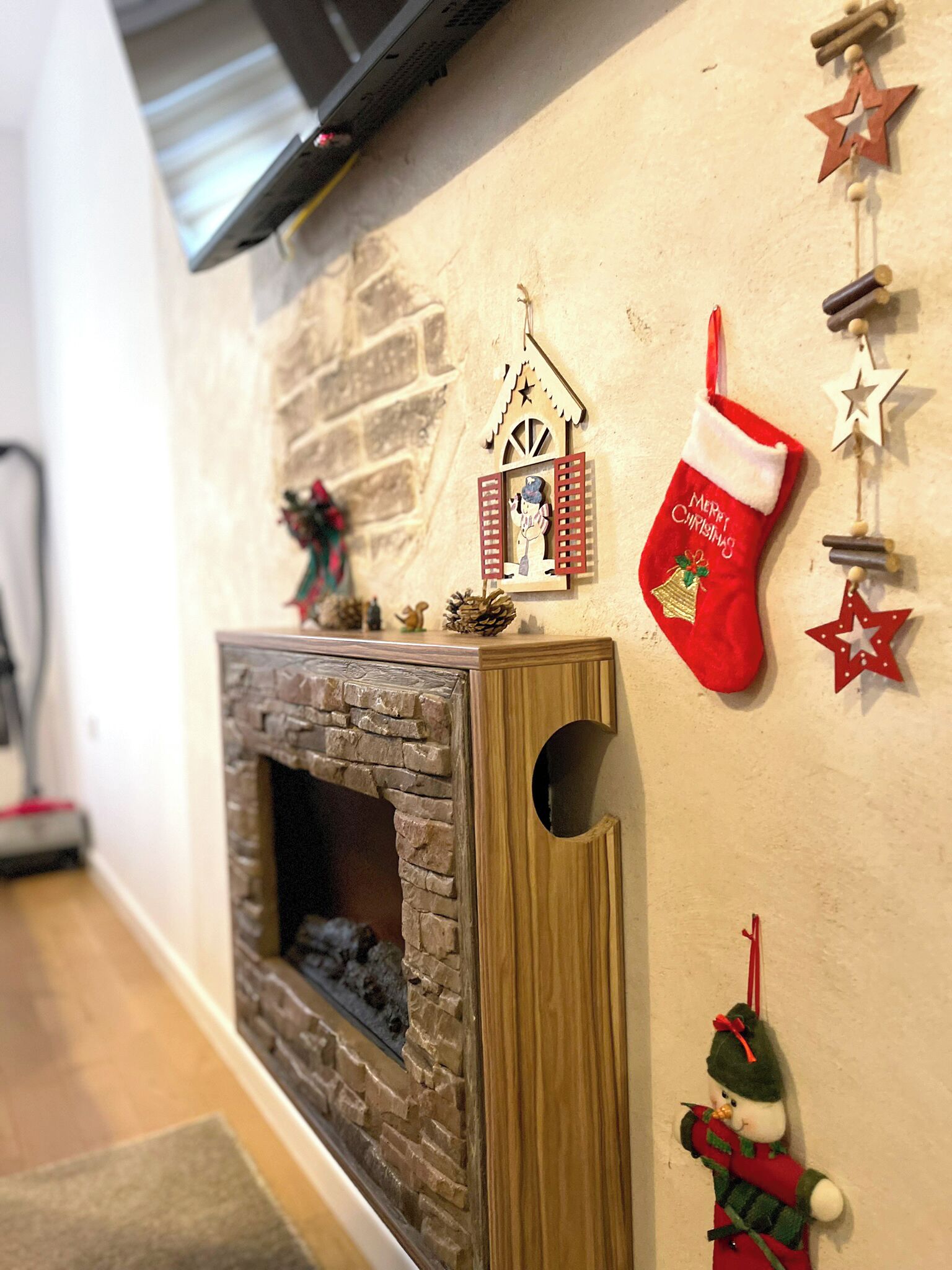 Une cheminée avec une façade en pierre, une manteau de cheminée en bois et une petite décoration de Noël.