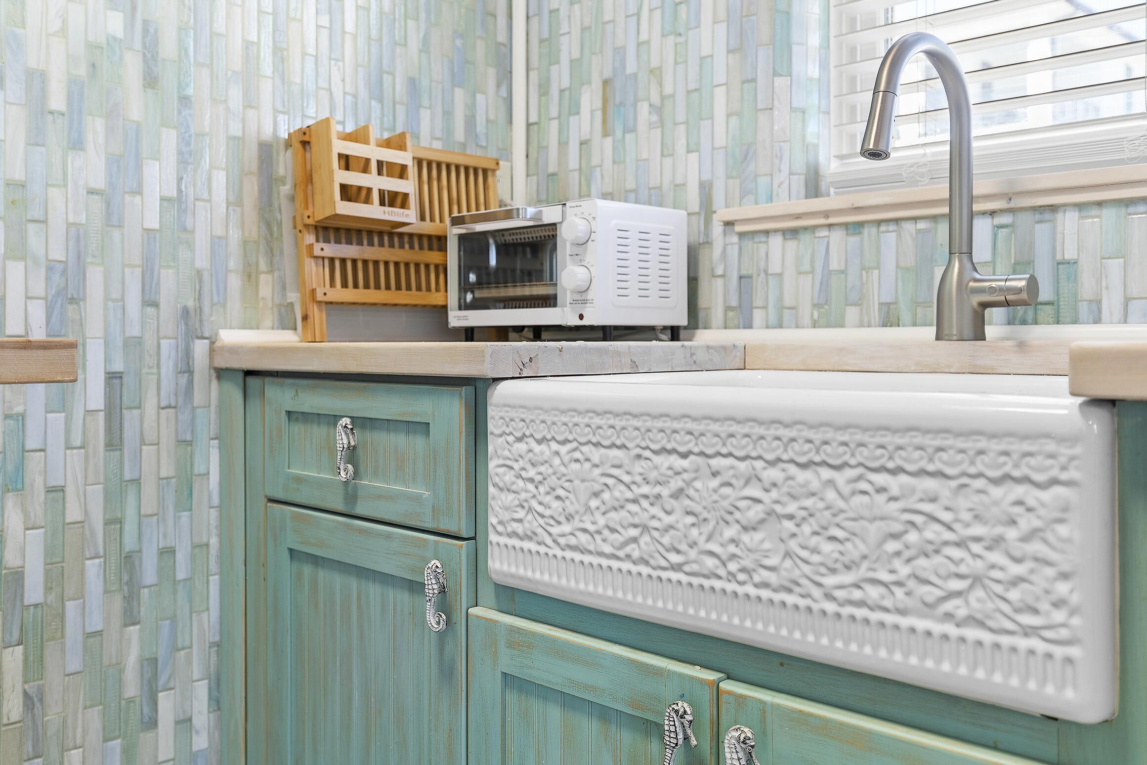 Una cocina con un lavamanos, un microondas y un contenedor de madera.