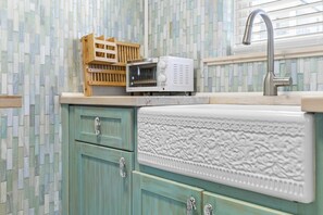 Una cucina con lavello, forno a microonde e una cassa di legno.