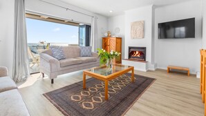 A modern living room with a glass coffee table, a sofa, a fireplace, and a large TV. - 19 Ascension (Cape Town)