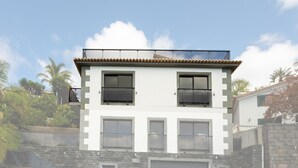 A two-story building with a garage, large windows, and a stone facade. - Skyline Villas Top - Fantastic sea view (Calheta)