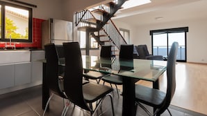 A modern kitchen with a glass dining table, black chairs, and a staircase leading to an upper level. - Skyline Villas Top - Fantastic sea view (Calheta)