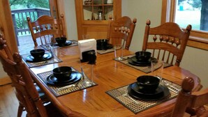 A wooden dining table set with black bowls and plates, surrounded by wooden chairs. - Keweenaw, Houghton/Hancock/MTU/Trails/Sauna (Houghton)