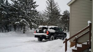 A snow-covered driveway with a pickup truck parked in front of a house. - Keweenaw, Houghton/Hancock/MTU/Trails/Sauna (Houghton)