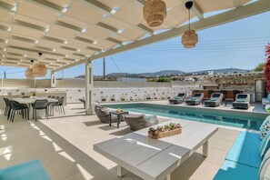 Un espace aménagé au bord de la piscine, comprenant un coin repas, des chaises longues et une vue sur le paysage.