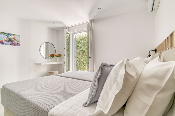 Une chambre à coucher moderne avec un grand lit, une table de chevet, un miroir et une fenêtre avec des rideaux.