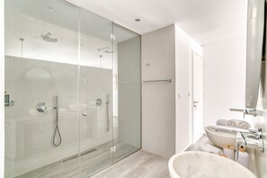 Ein modernes Badezimmer mit einer gläsernen Duschkabine, einem großzügigen Marmorwaschbecken und einer Toilette.