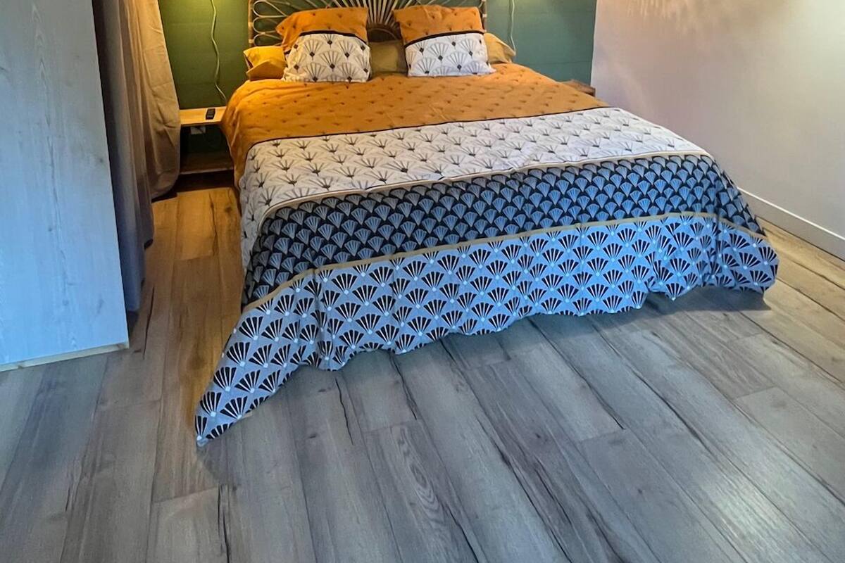 A bedroom with a bed, wooden ceiling beams, green walls, and two wall-mounted lights.