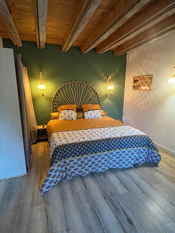 A bedroom with a bed, wooden ceiling beams, green walls, and two wall-mounted lights. - La Colonie d'Antan (Collonges)
