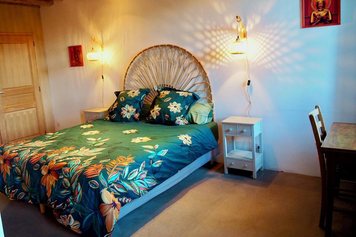 A bedroom with a bed, bedside tables, a chair, and a wall-mounted light fixture.