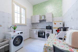 A compact kitchen with a washing machine, microwave, oven, and a dining area with a table.