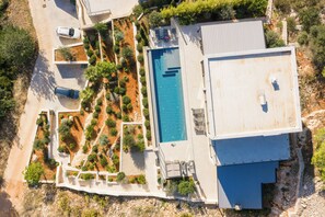Vista aérea de una casa moderna con piscina, terraza cubierta y jardín ajardinado.