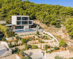 A modern two-story house with a swimming pool, stone retaining walls, and a lush garden. - Incredible divine view 5-bedroom villa in Vis Town (Vis)