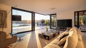 A modern living room with a large TV, comfortable seating, and a view of a lake. - Incredible divine view 5-bedroom villa in Vis Town (Vis)