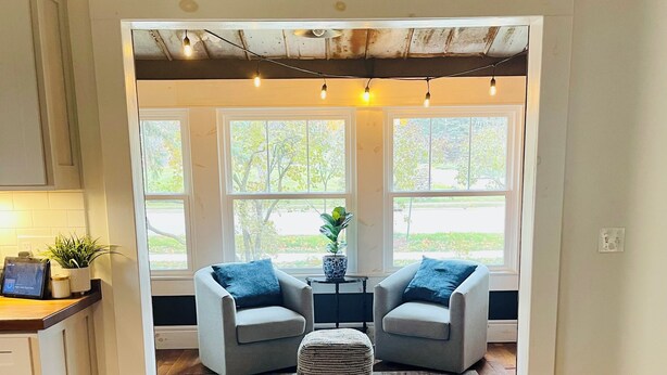 A cozy dining area with two chairs, a small table, and a sign above reading 'let's eat.' - Spacious 4BR Retreat Near Downtown Elk Rapids. Walk to Shops, Dining & the Bay (Elk Rapids)