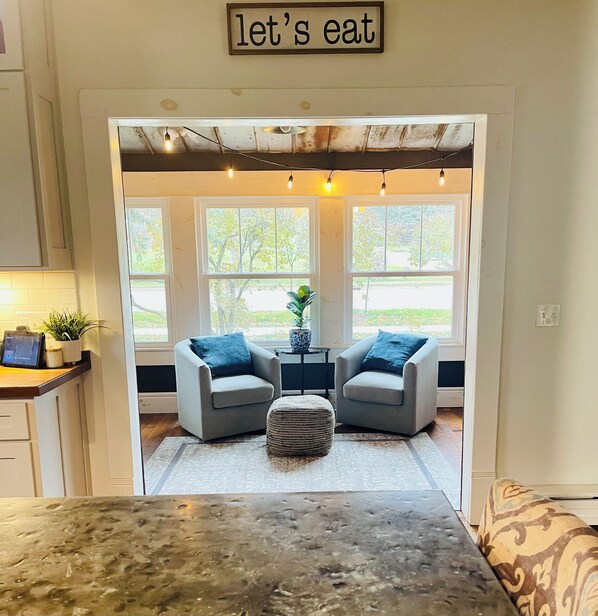 A cozy dining area with two chairs, a small table, and a sign above reading 'let's eat.'
