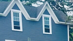A two-story house with a gabled roof, multiple windows, and a small tree in front. - Spacious 4BR Retreat Near Downtown Elk Rapids. Walk to Shops, Dining & the Bay (Elk Rapids)