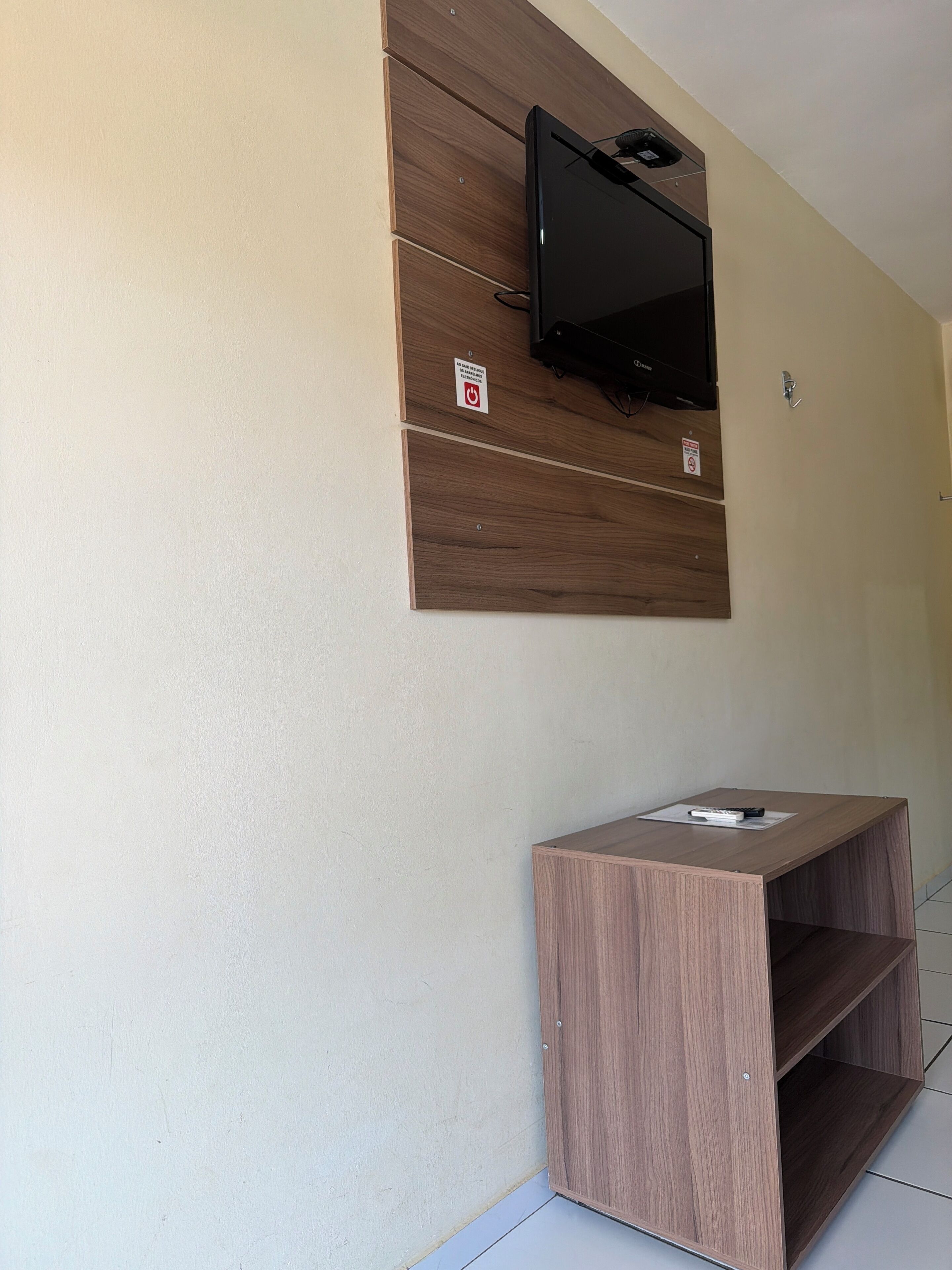 Un baño con tocador de madera, televisor montado y toallero.