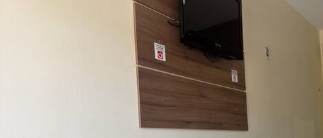 Un baño con tocador de madera, televisor montado y toallero.