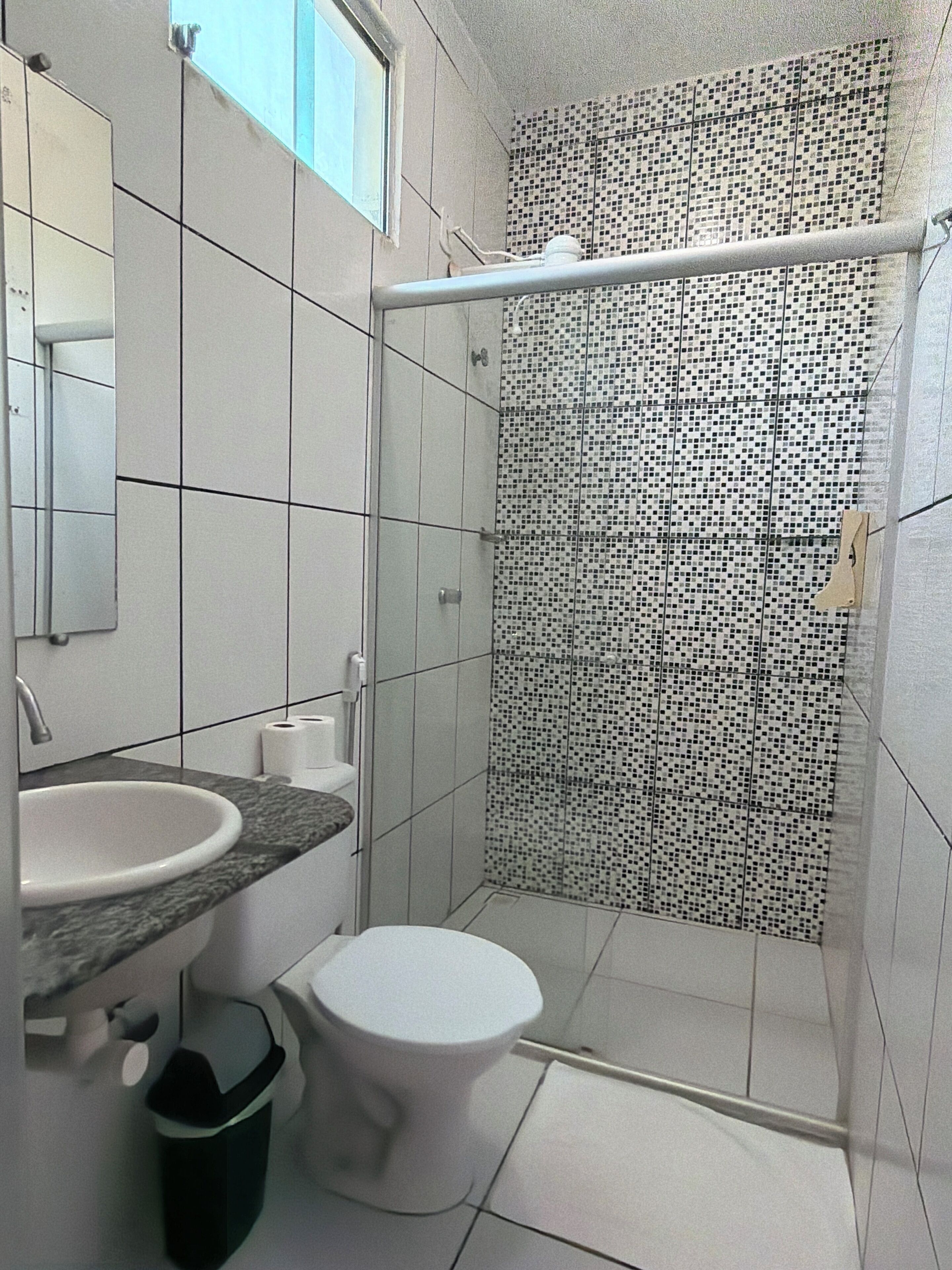 A bathroom with a white sink, a toilet, and a shower with a tiled wall.