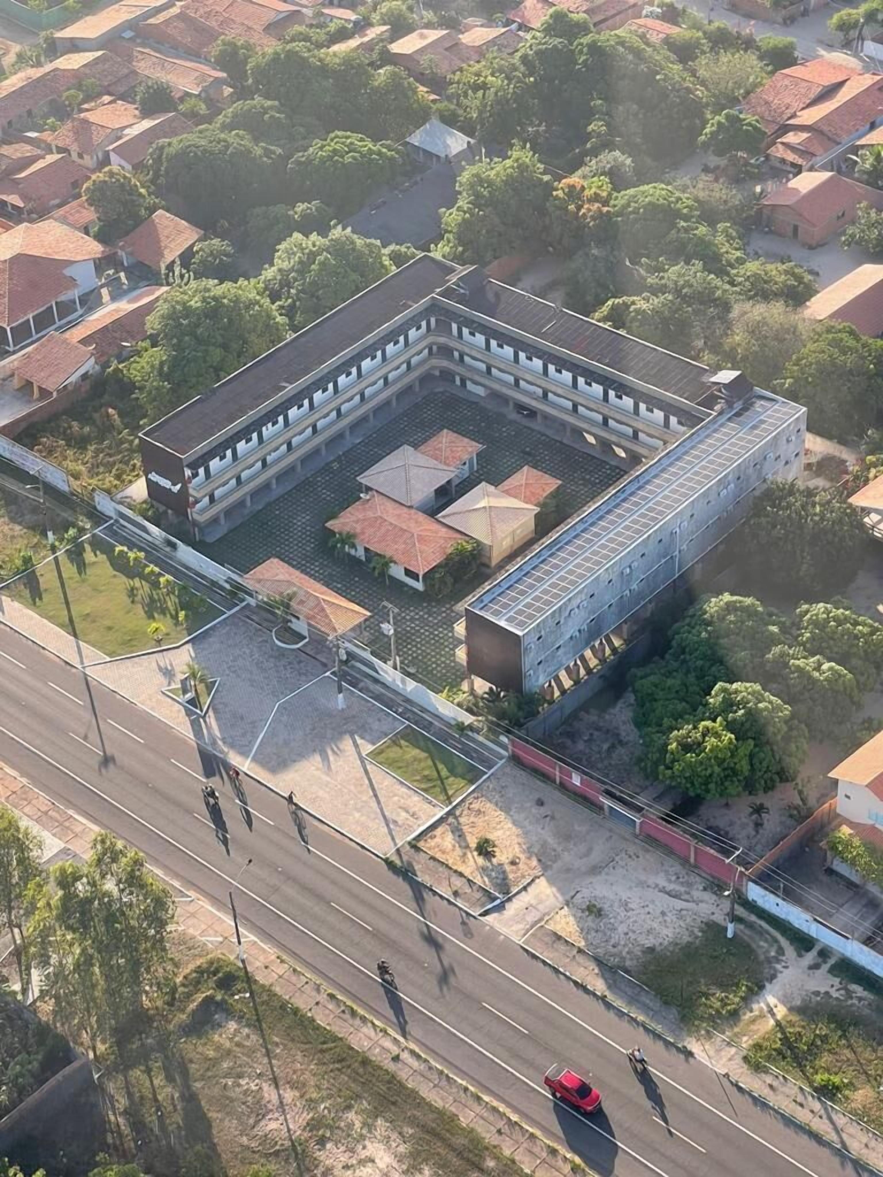An aerial view of a building with a central courtyard, surrounded by a road and residential areas.