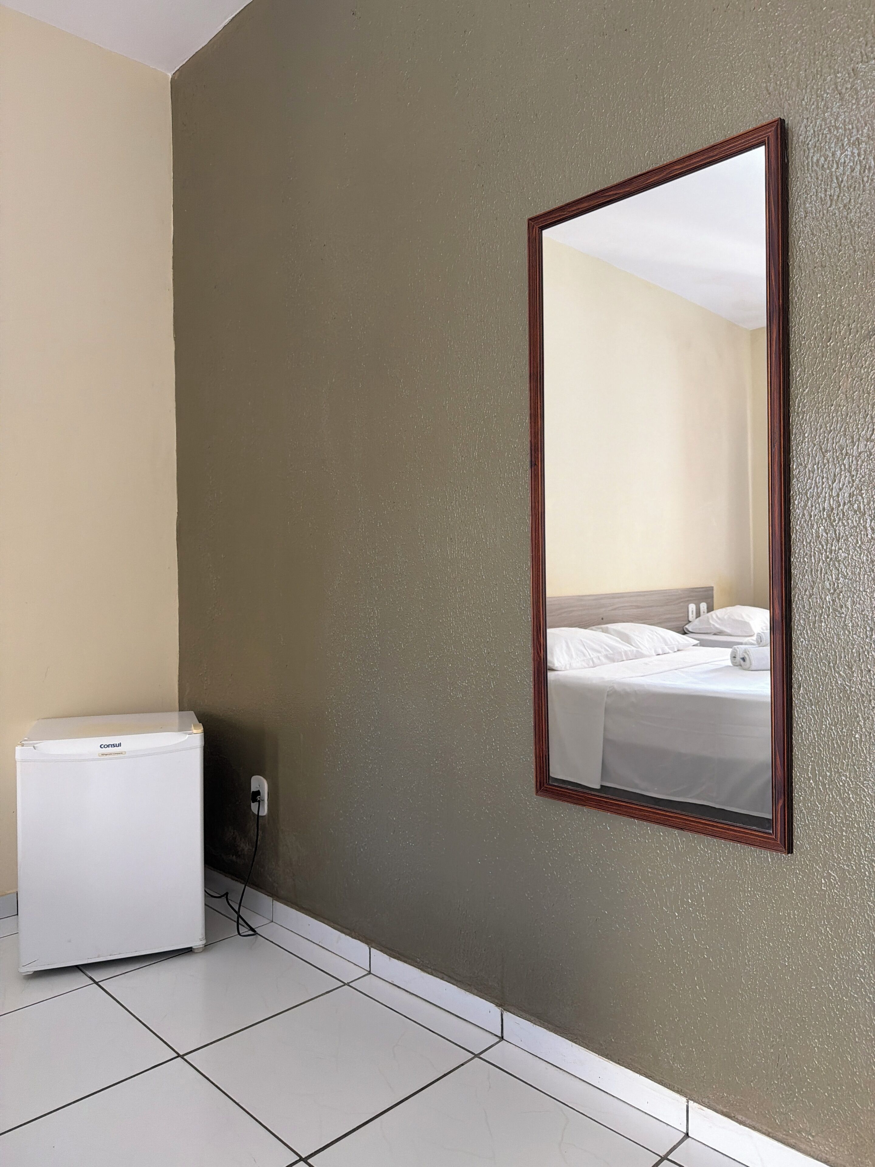 Una habitación de hotel con una cama, una mesita de noche y un calentador blanco.