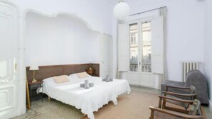 Ein Schlafzimmer mit Bett, Nachttischen, einer Lampe, einem Sessel und einem Heizkörper.