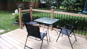 A wooden deck with a glass table and four chairs. - Forest City (room for one person) #3 (London)