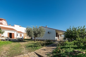 Un bâtiment blanc avec un toit rouge, un chemin pavé et un petit arbre au premier plan.