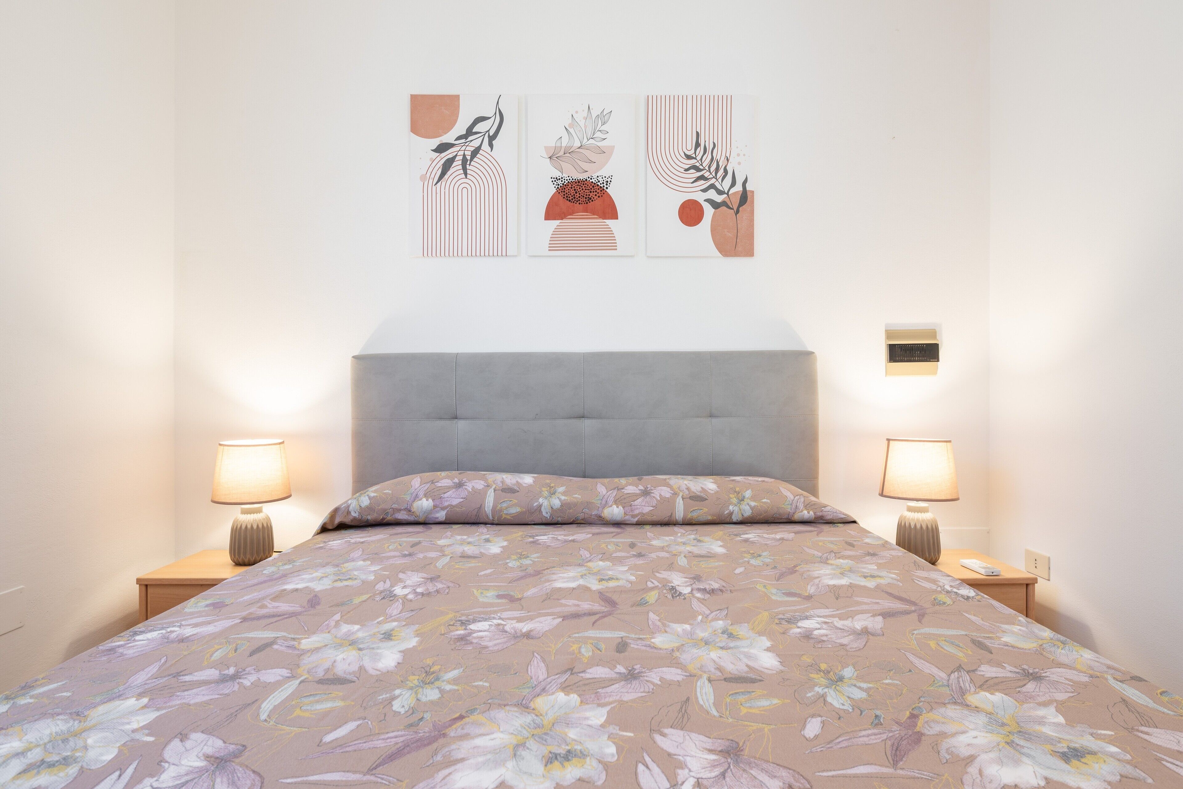 Una camera da letto con un letto, due comodini, una testiera e tre opere d'arte appese al muro.