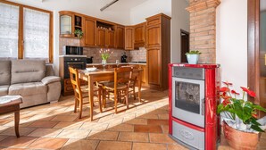 Eine Küche mit Holzschränken, einem roten Herd und einem Essbereich mit Tisch und Stühlen.