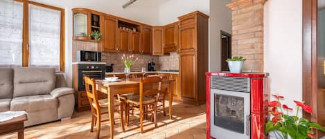 Una cocina con gabinetes de madera, una estufa roja y un comedor con mesa y sillas.