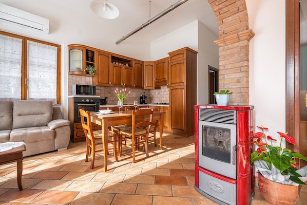 A kitchen with wooden cabinets, a red stove, and a dining area with a table and chairs.