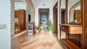 Ein Korridor mit Backsteinwand, Holzschränken, einem Kamin und einem Blumentopf.