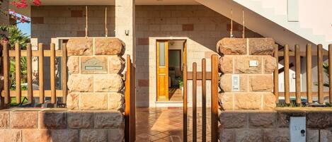 A stone gate with a wooden fence, a tiled entrance, and a staircase leading to a building.