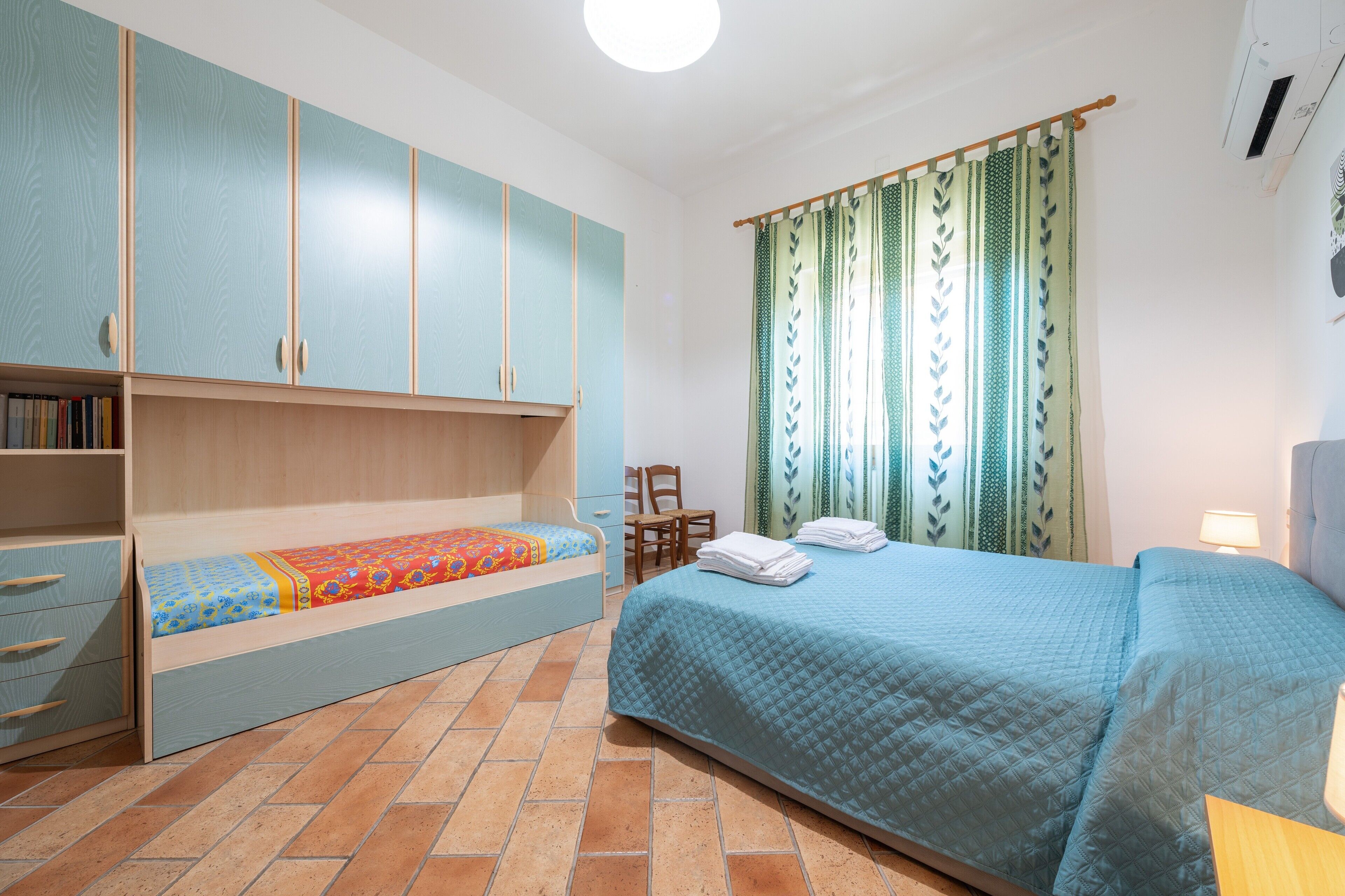 A bedroom with a bed, a wardrobe, a desk, and a chair.