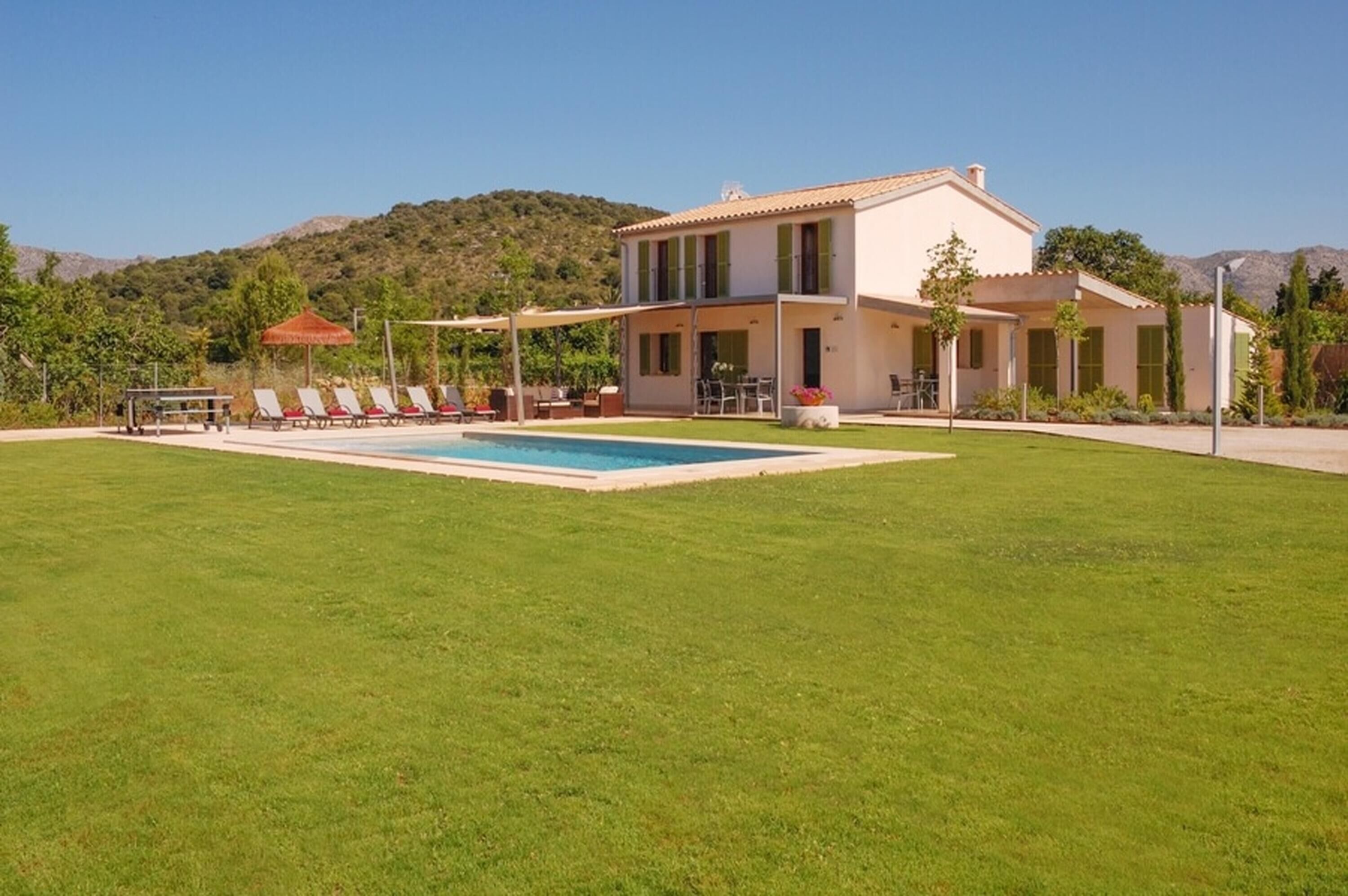 A two-story house with a swimming pool, a covered patio, and a well-maintained lawn.