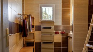 Une salle de bain avec un banc en bois, un porte-serviettes et une fenêtre.